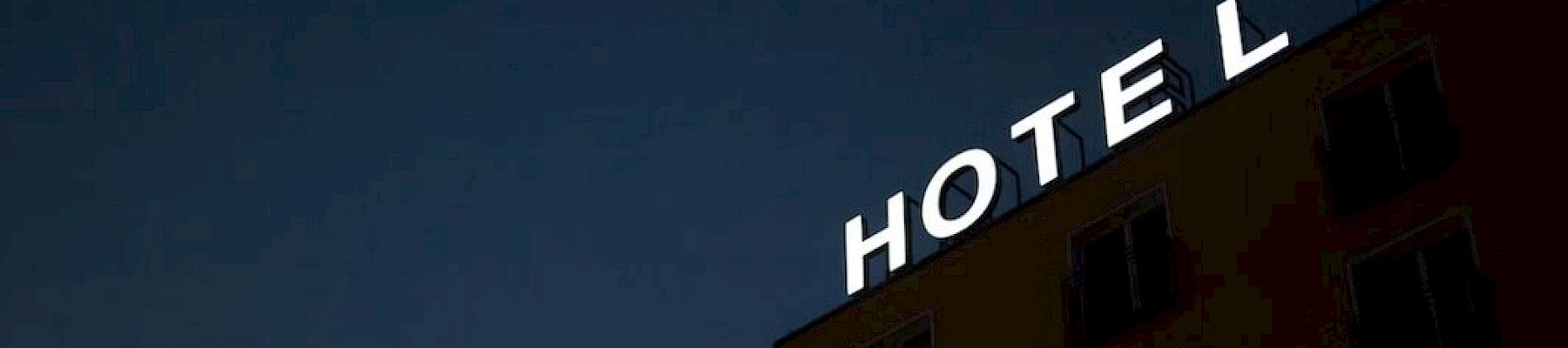 A building with a neon "HOTEL" sign, at night, missing the letter "T".