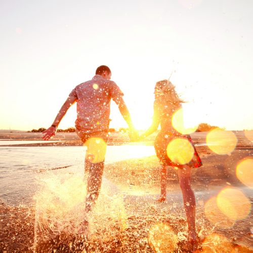 A sunlit family walks along a beach at sunset, footprints trailing in the sand, carrying a child toward the glowing horizon.